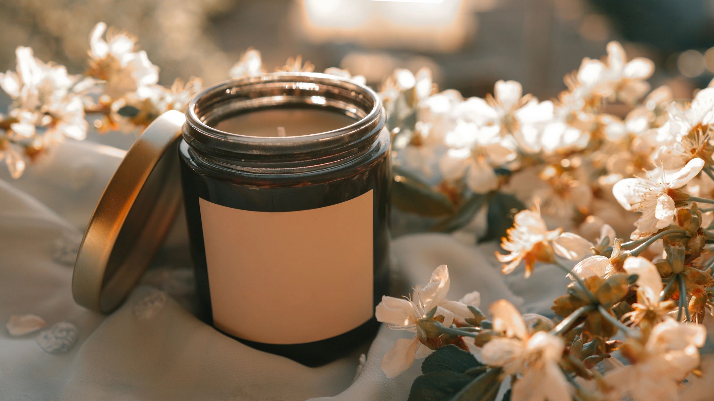 Amber glass candle with delicate blossoms styled for a premium wellness brand